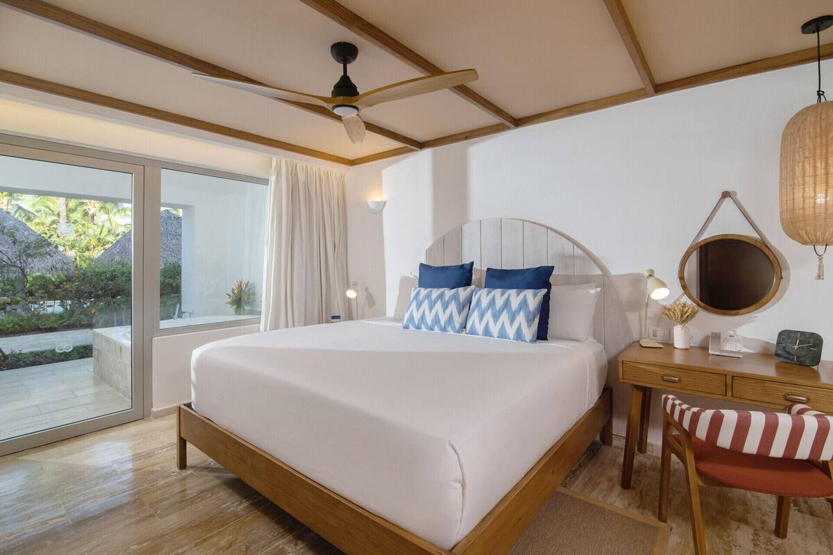 Un dormitorio con cama, mesita de noche, silla y ventilador de techo.