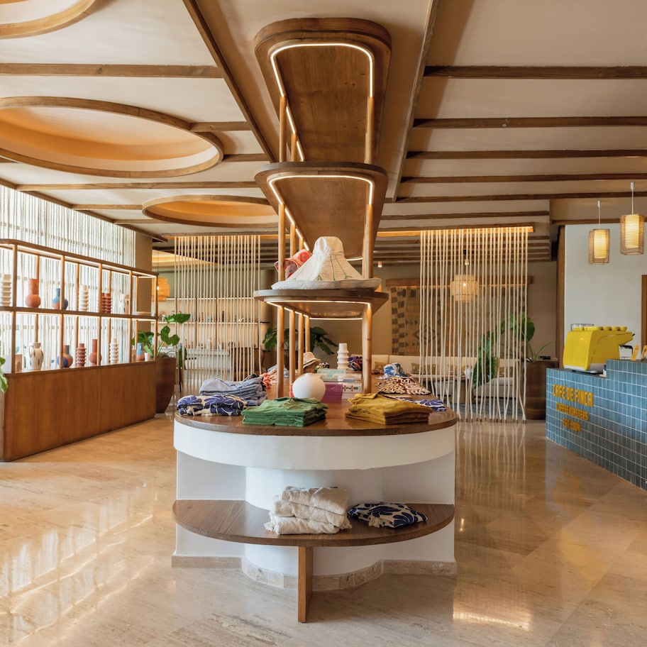 A modern reception area with a central circular display, wooden beams on the ceiling, and a reception desk with a blue tiled counter.