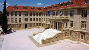 Un grand bâtiment historique à la façade symétrique, doté de nombreuses fenêtres et d’une cour intérieure avec un escalier menant aux étages supérieurs.