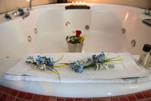 A bathtub with a towel and flowers. - Anastazia Luxury Suites & Rooms (Dionysos)