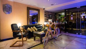 Un hall d’entrée avec un canapé en cuir, une table basse en bois, un vélo et un miroir.
