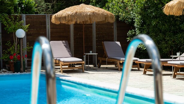 Une piscine avec des chaises longues et des parasols en chaume.