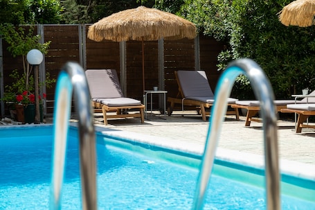 Una piscina al aire libre, sombrillas, sillones reclinables de piscina