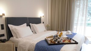 Une chambre d’hôtel avec un grand lit, une table de chevet, un plateau avec des articles pour le petit-déjeuner et une fenêtre avec des rideaux.