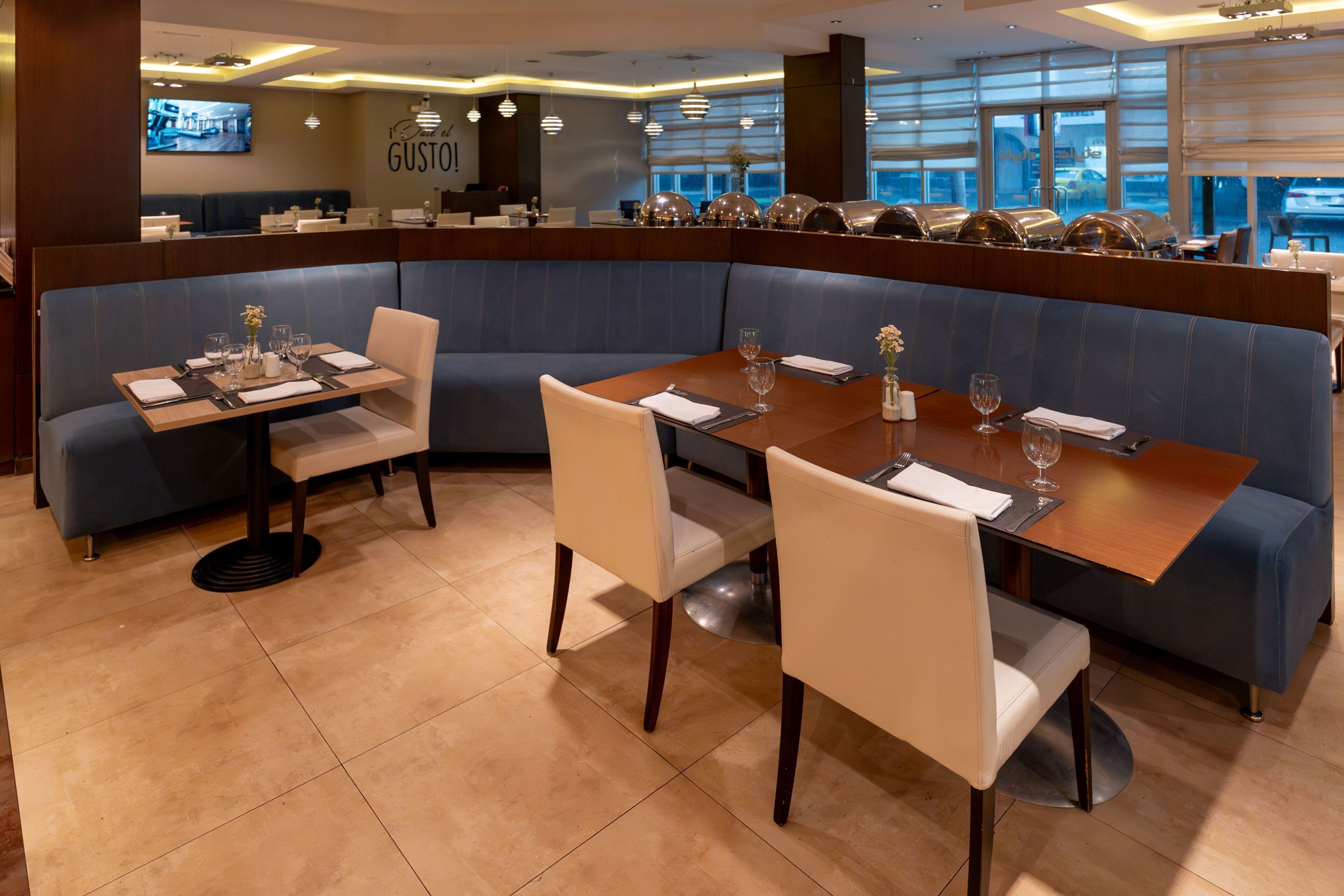 Un ristorante con interni moderni, che offre diverse disposizioni di posti a sedere, tra cui cabine e tavoli, e un'ampia vetrata con vista sulla strada.