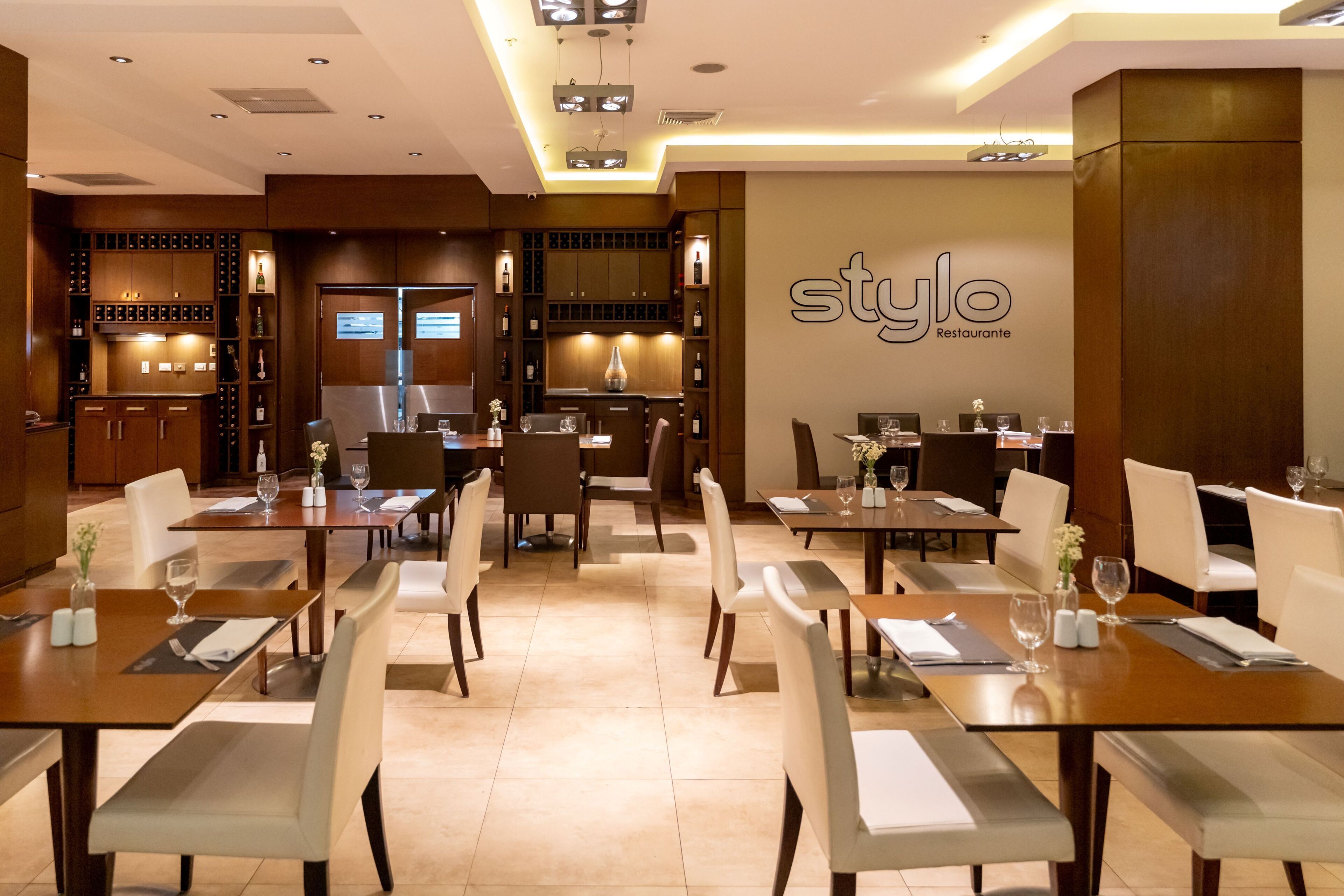A restaurant interior with multiple dining tables, chairs, and a wall sign reading 'style Restaurante'.