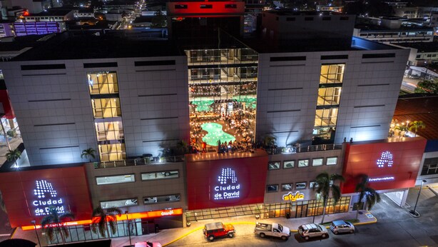 A hotel with multiple floors, large windows, and a central atrium with a green-lit area. - Hotel Ciudad De David (David)