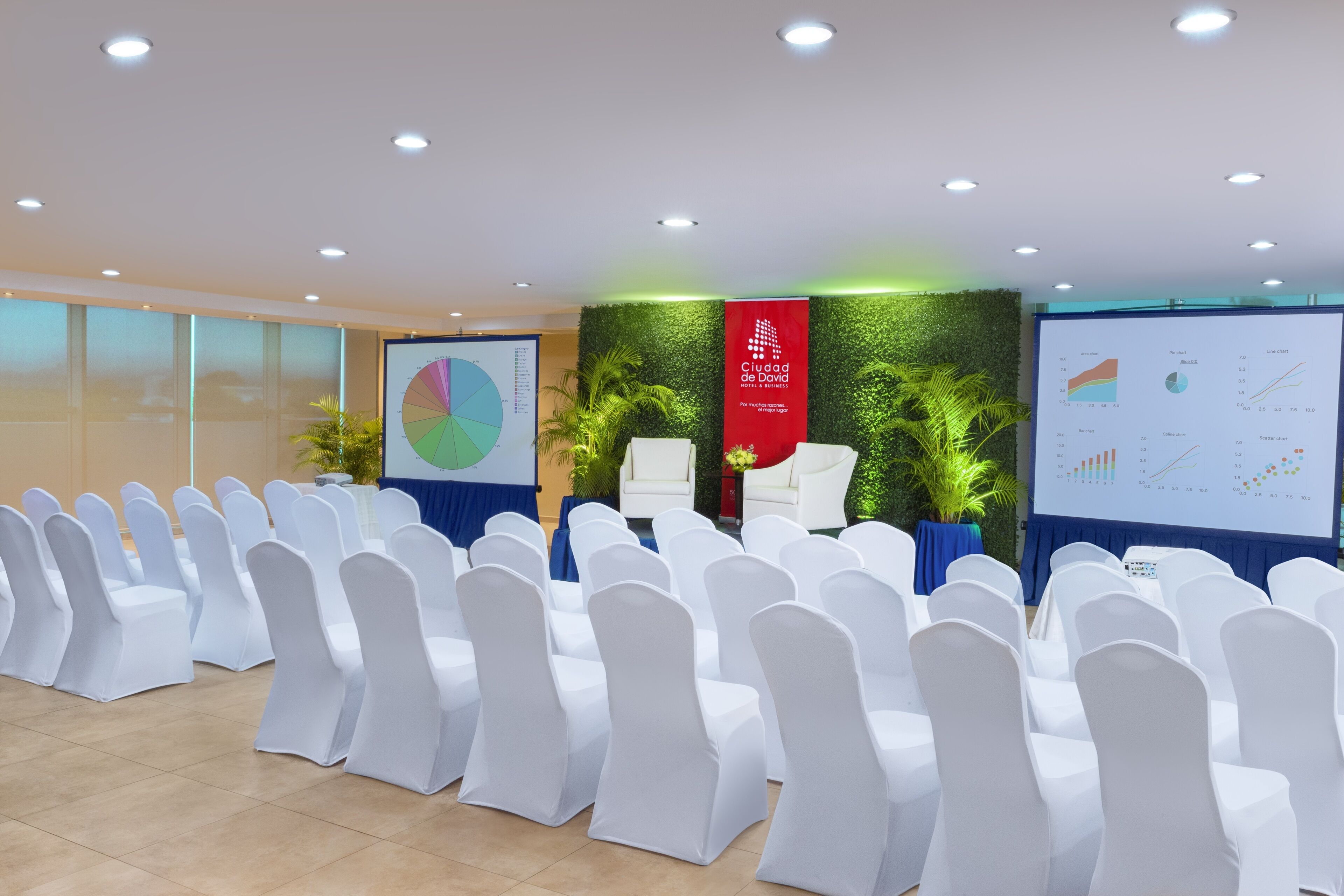 A conference room with rows of white chairs, a presentation screen, and a banner reading "Ciudad de Davao."