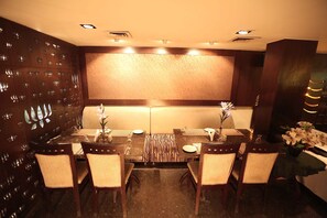 A dining area with a long table, six chairs, and a patterned wall. - Shanti Palace (New Delhi)