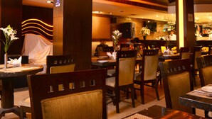 A restaurant interior with wooden chairs, tables, and a bar area. - Shanti Palace (New Delhi)