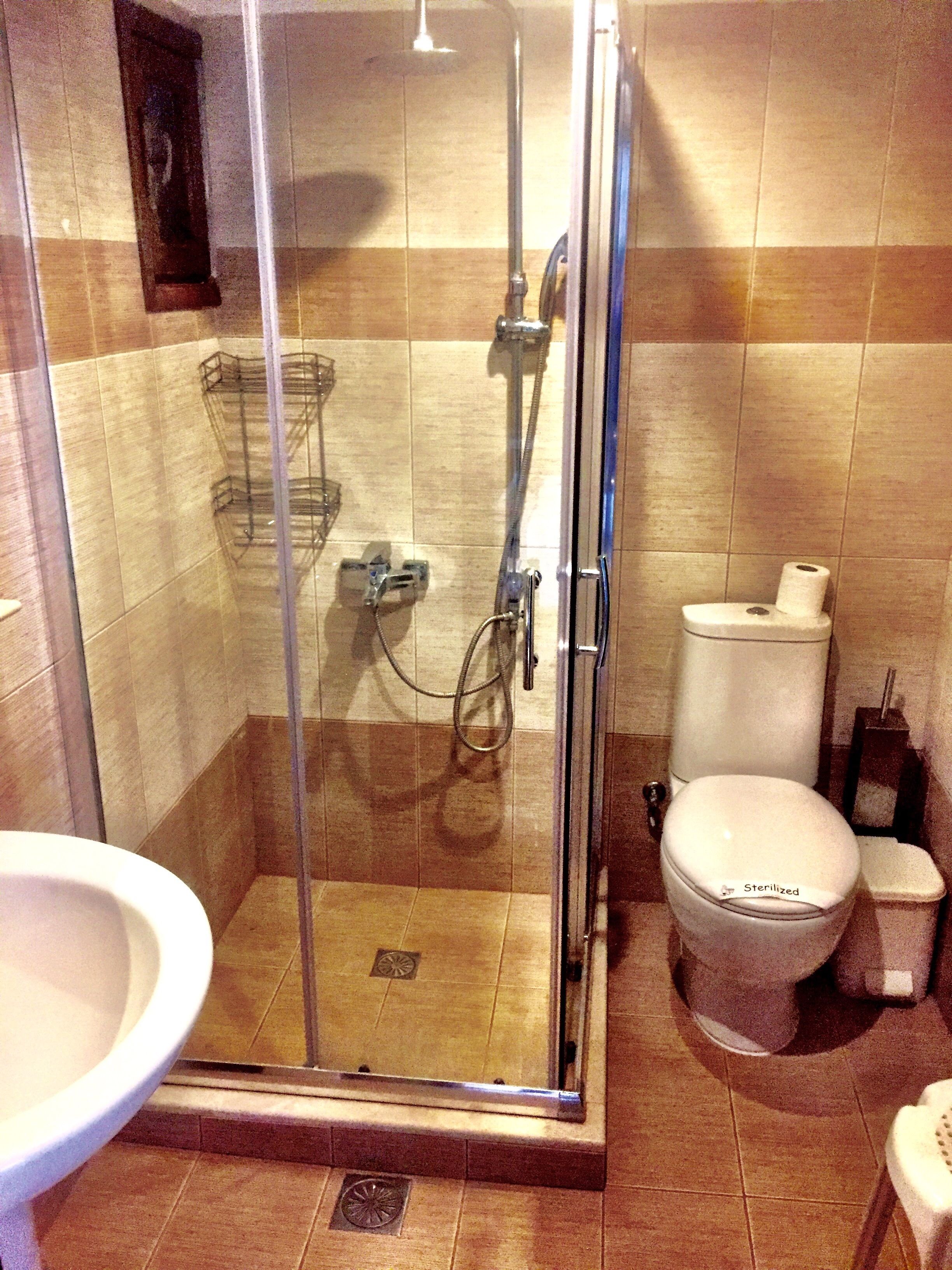Een badkamer met een douchecabine van glas, toilet en wastafel.