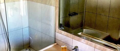 A bathroom with a sink, mirror, and shower.