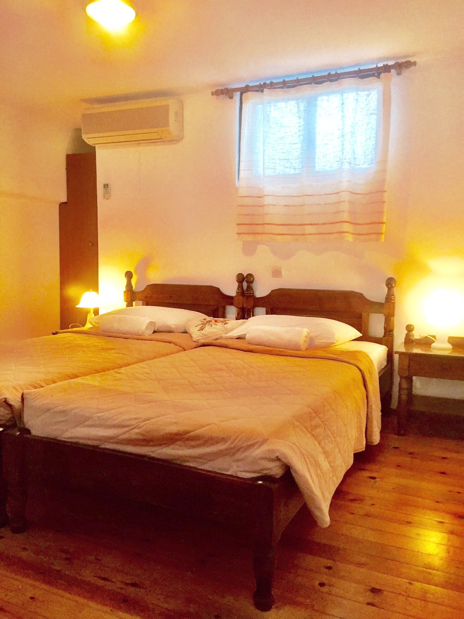 Una cama doble con cabecera de madera, dos mesitas de noche y un ventanal con cortinas.