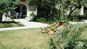 A building with a courtyard, outdoor seating, and lush greenery. - Irene Villas (Ierapetra)