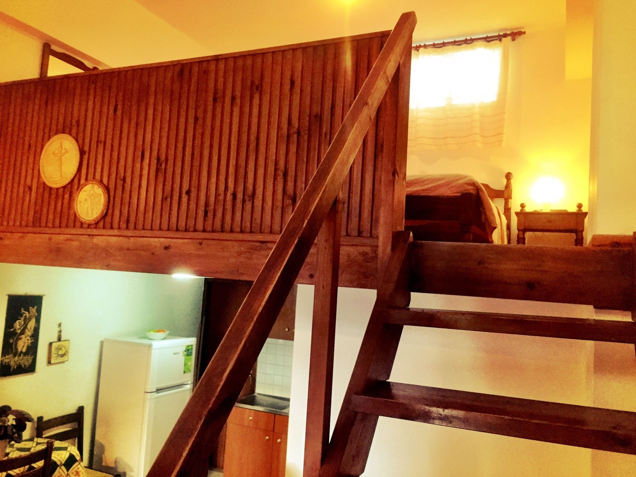 A wooden bunk bed with a ladder, a small table, and a bed with a blanket.