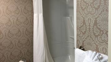 A bathroom with a bathtub, a shower curtain, a towel rack, and a toilet paper holder.