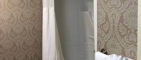 Un baño con bañera, cortina de ducha, toallero y soporte para papel higiénico.