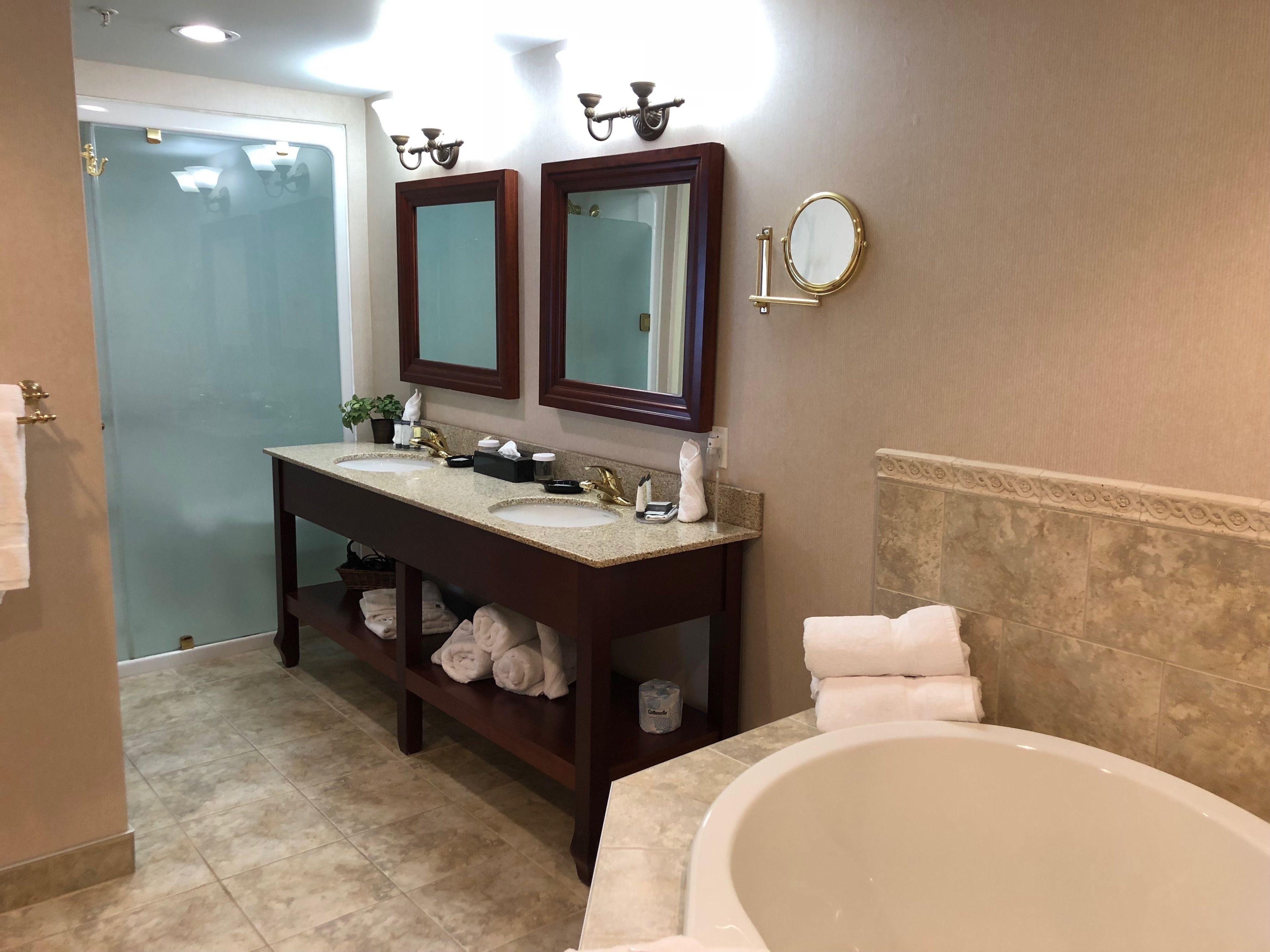 A bathroom with two sinks, a vanity, a bathtub, and a mirror.