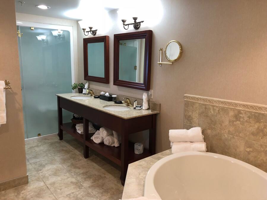 Un baño con dos lavamanos, tocador, bañera y espejo.