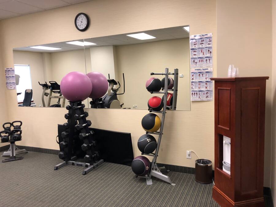 Un gimnasio con equipo de ejercicio, un reloj y carteles instructivos en la pared.