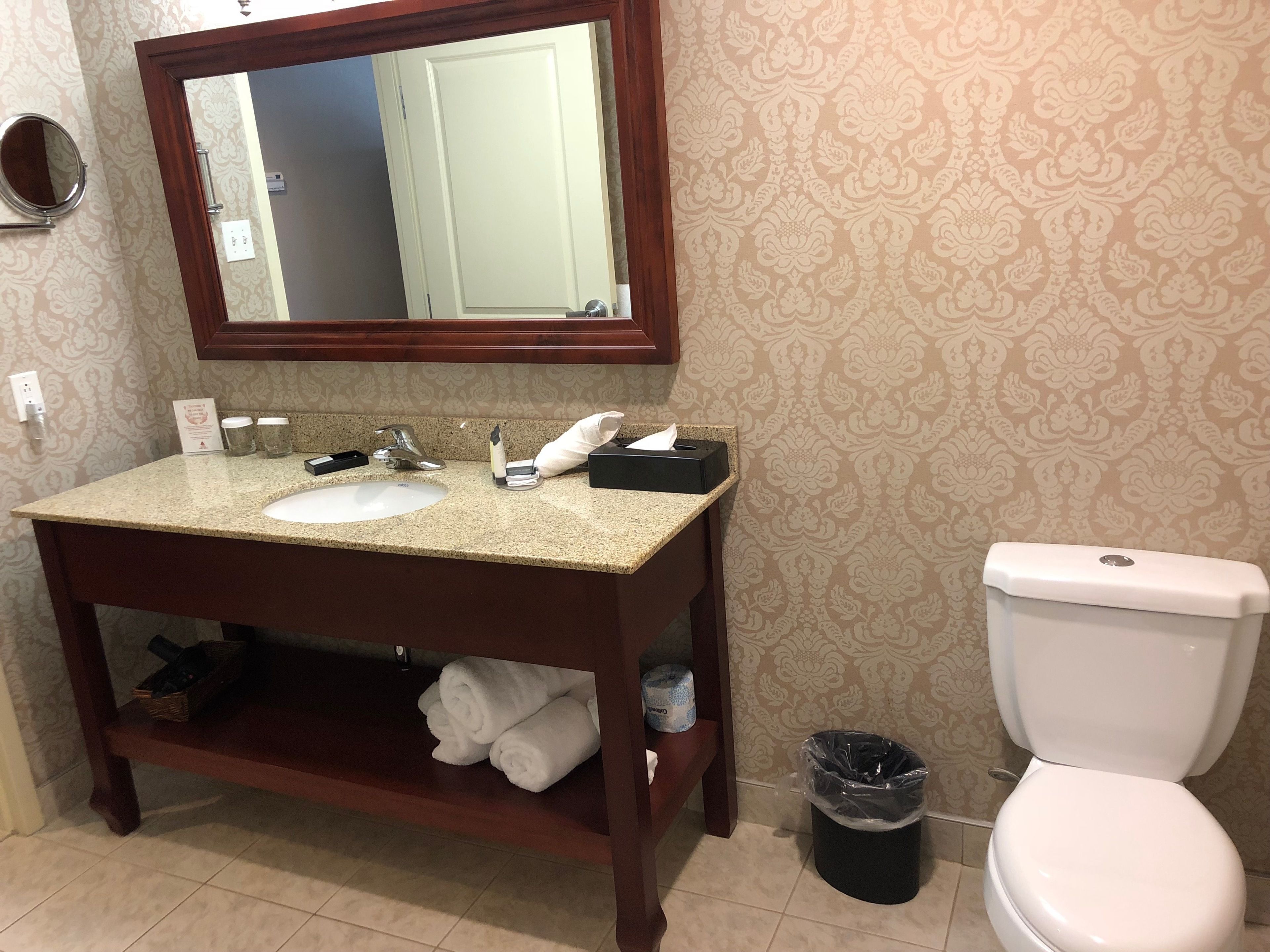 Une salle de bain équipée d’un lavabo, d’un miroir, d’un porte-serviettes et de toilettes.