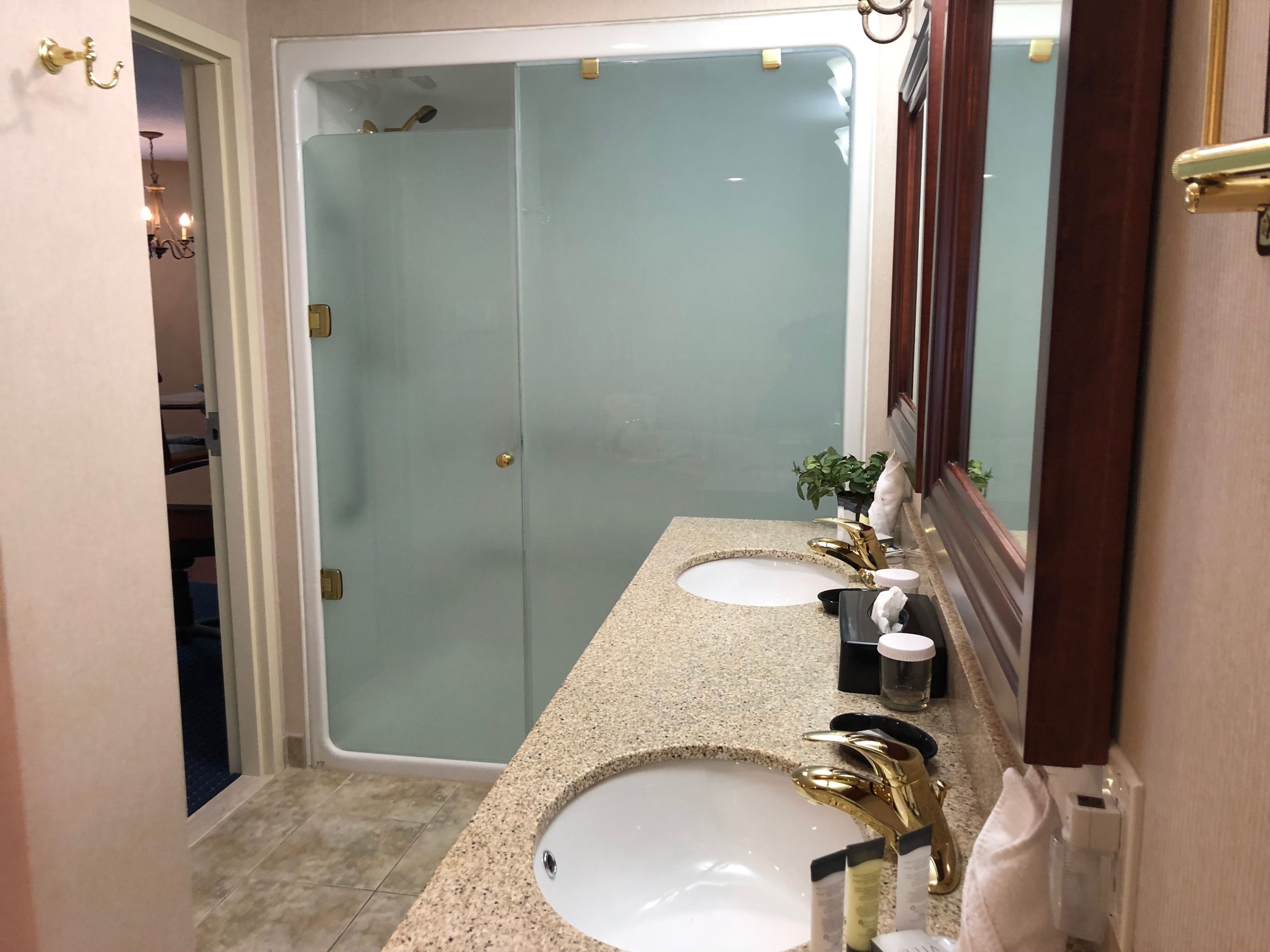 Une salle de bain avec deux lavabos, une douche et un grand miroir.
