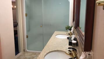 Une salle de bain avec deux lavabos, une douche et un grand miroir.