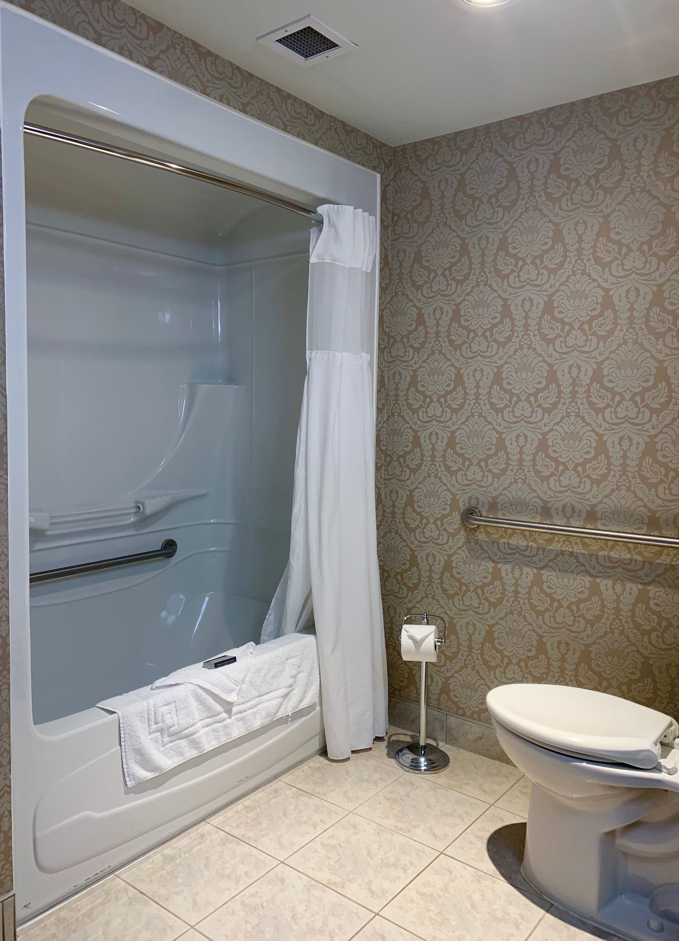 A bathroom with a bathtub, toilet, and shower curtain.