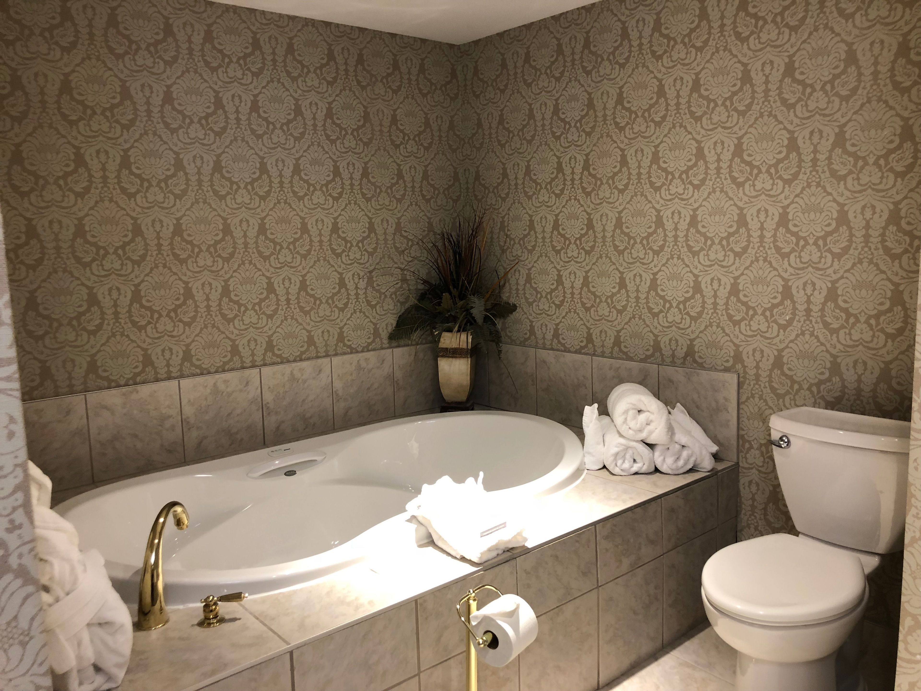 A bathroom with a bathtub, toilet, and a towel rack with towels.