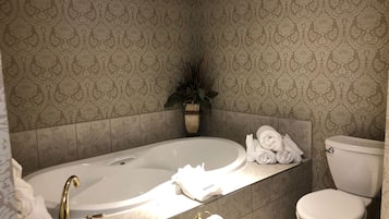 A bathroom with a bathtub, toilet, and a towel rack with towels.