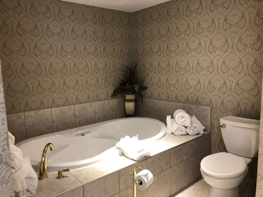 A bathroom with a bathtub, toilet, and a towel rack with towels.