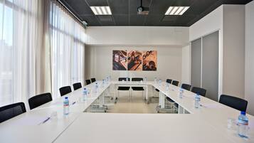 Un salón de conferencias con una larga mesa, sillas y botellas de agua.
