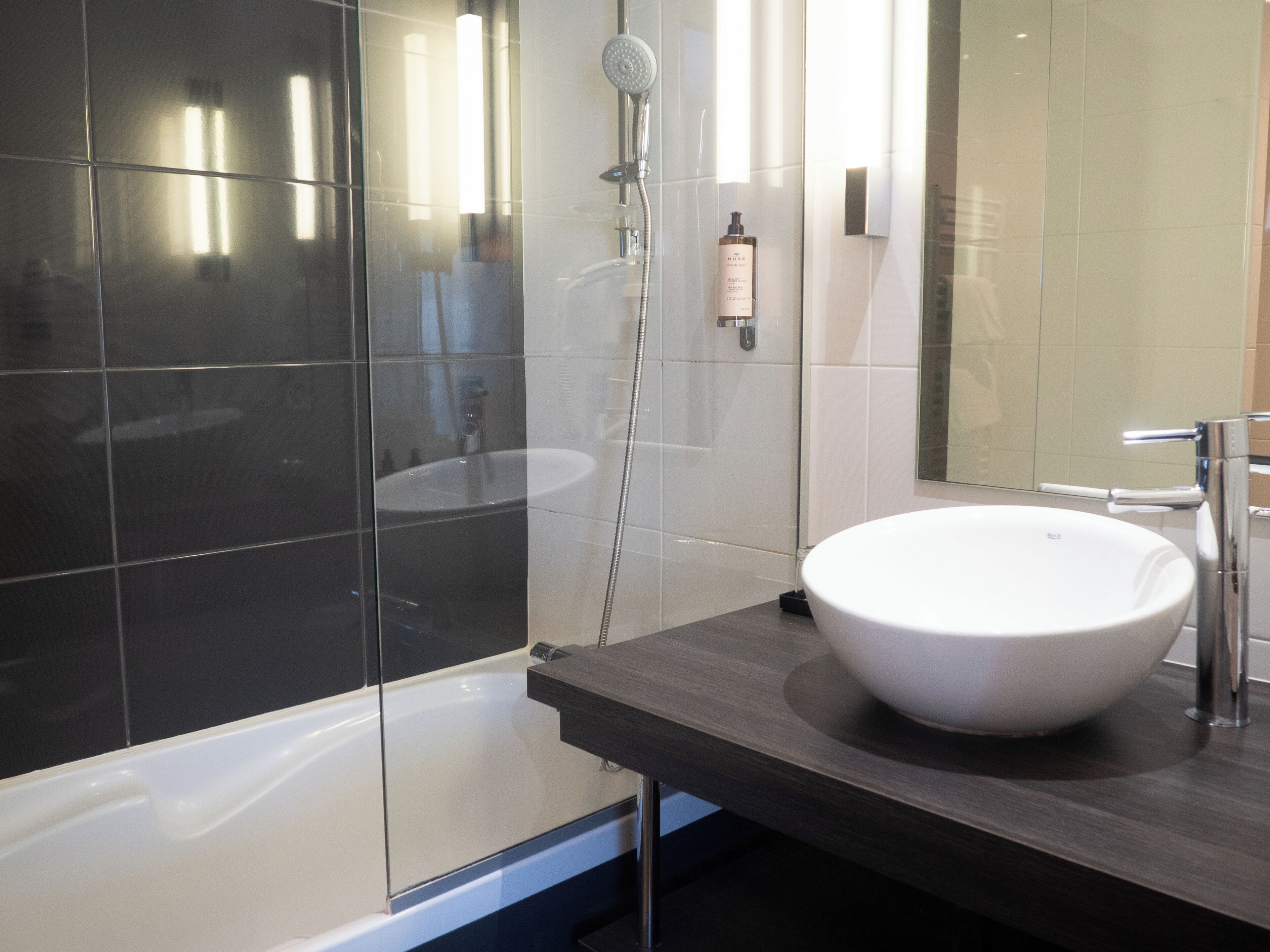 A modern bathroom with a large bathtub, a white sink, and a glass shower enclosure.