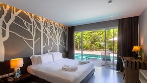 A modern hotel room with a large bed, a desk with a laptop, a telephone, and a view of a swimming pool and greenery outside. - Panalee Koh Samui Resort (Koh Samui)