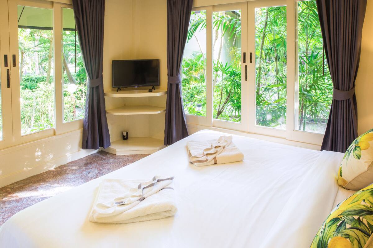 Habitación de hotel con cama, televisión y ventana con cortinas.