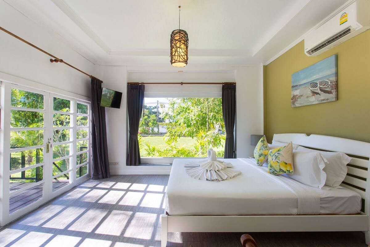 Una habitación de hotel con cama, televisor, un cuadro y vistas a zonas verdes.