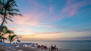 A beachside setting with lounge chairs and a palm tree, overlooking the sea. - Panalee Koh Samui Resort (Koh Samui)