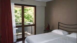 Un dormitorio con cama, ventana y vistas al verdor exterior.