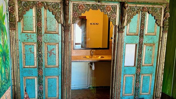 Una habitación de diseño tradicional, con una puerta de madera con tallas intrincadas y un espejo sobre un lavamanos.