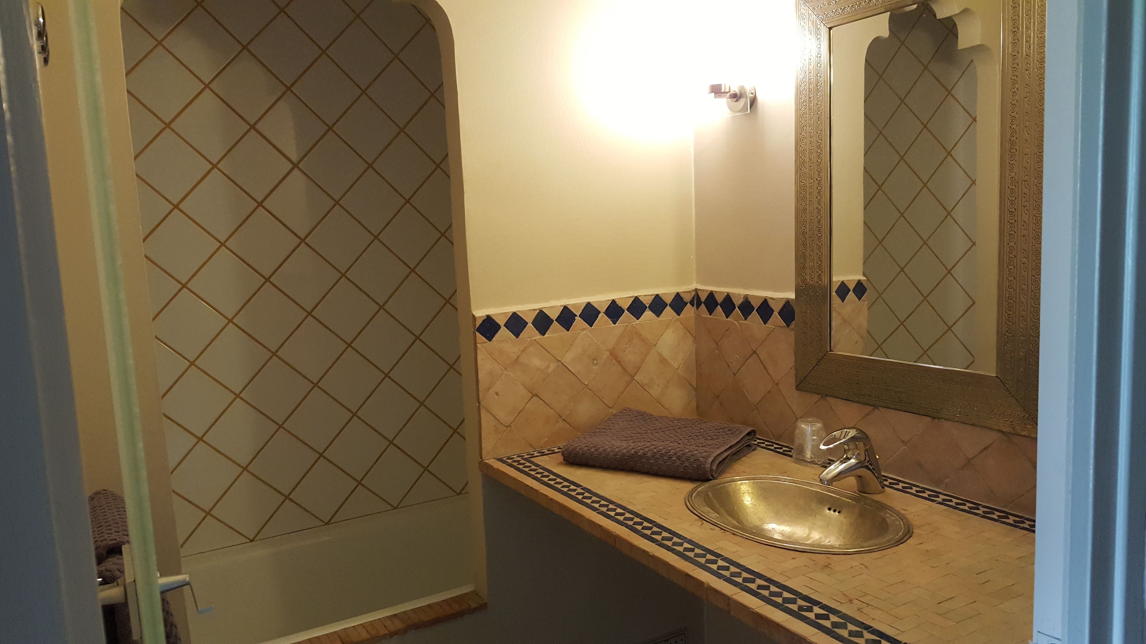 Un baño con lavamanos, espejo y azulejos estampados.