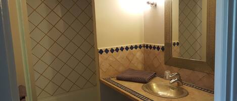 Un baño con lavamanos, espejo y azulejos estampados.