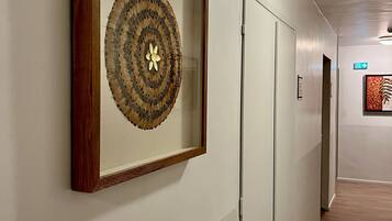 A hallway with a framed artwork on the wall, a door, and a light fixture.