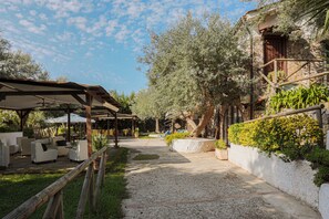 An outdoor patio area with seating, a pergola, and a stone wall with greenery. - Relais il Frantoio - Apartments (Massa Lubrense)