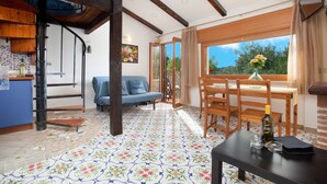 Una habitación con una mesa de comedor de madera, sillas, un sofá y una zona de cocina con estufa.