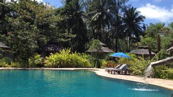 Una piscina al aire libre, sombrillas, sillones reclinables de piscina