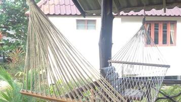 A hammock suspended between wooden beams, with a view of a building in the background.