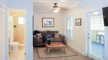 A living room with a ceiling fan, a sofa, a coffee table, and a door leading to a balcony.
