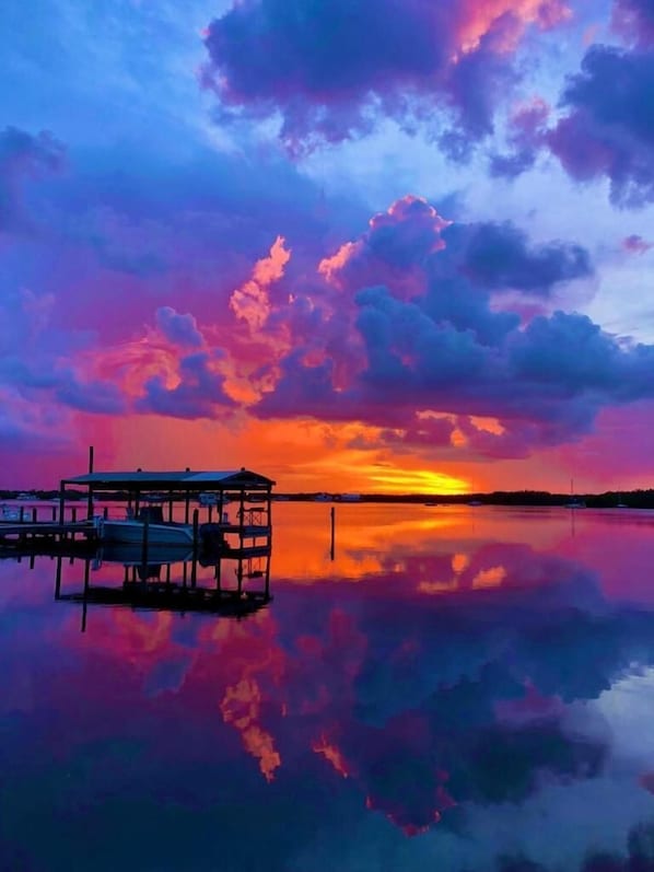 A sunset over a calm body of water with a dock and a small structure. - Coconut Palm Inn (Tavernier)