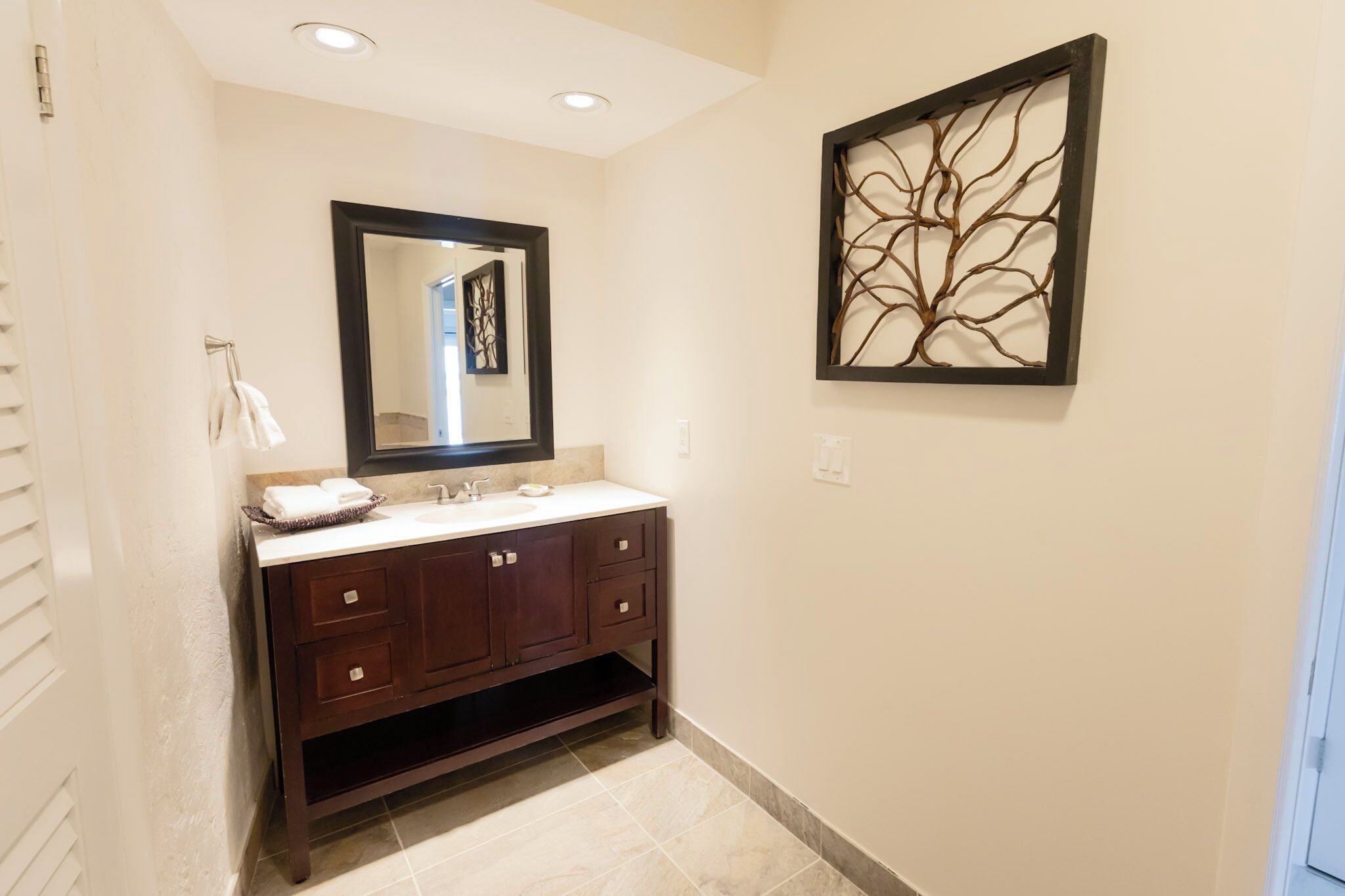Un baño con tocador de madera oscura, un espejo y una obra de arte en la pared.