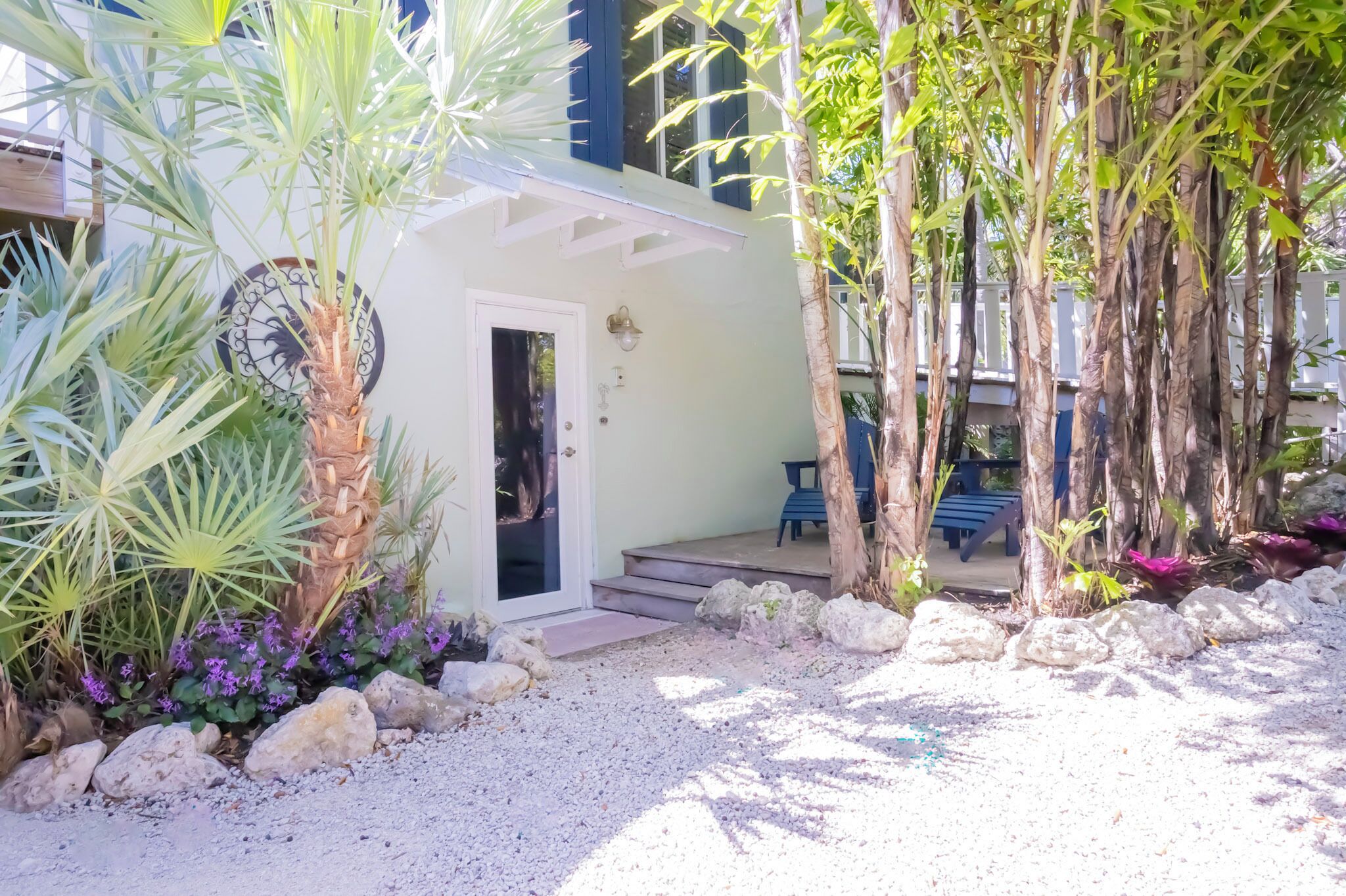 A covered outdoor seating area with a door, surrounded by plants and rocks.